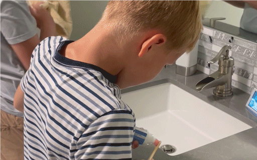 Child brushing teeth with The Smilen interactive device on bathroom counter