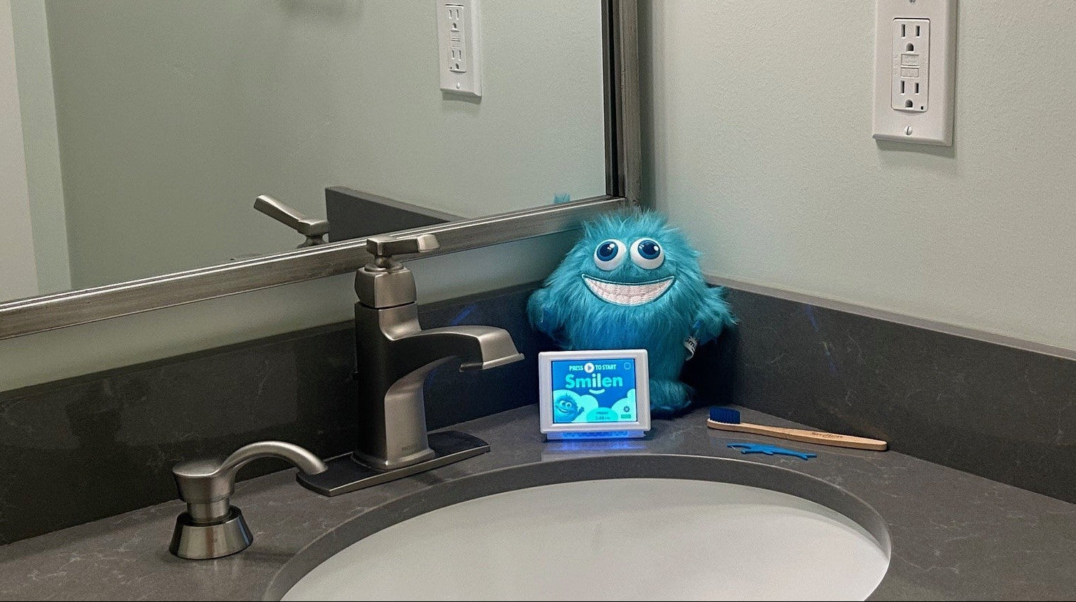 Bathroom sink with a blue plush toy and small device on the counter.